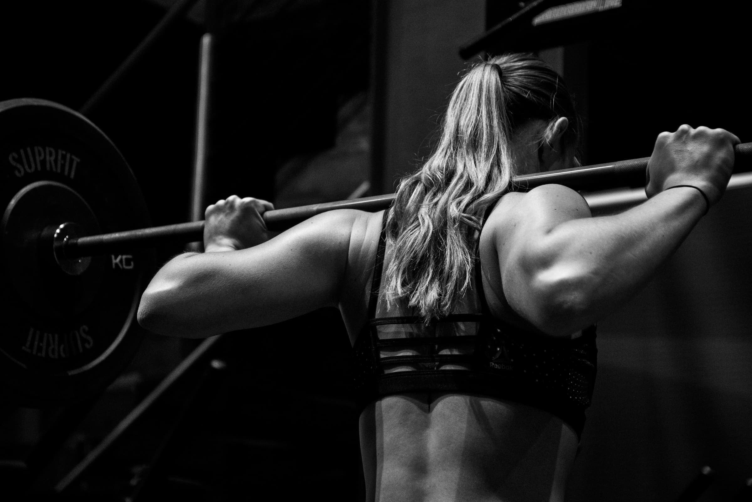 A woman with a barbell across her shoulders, about to squat